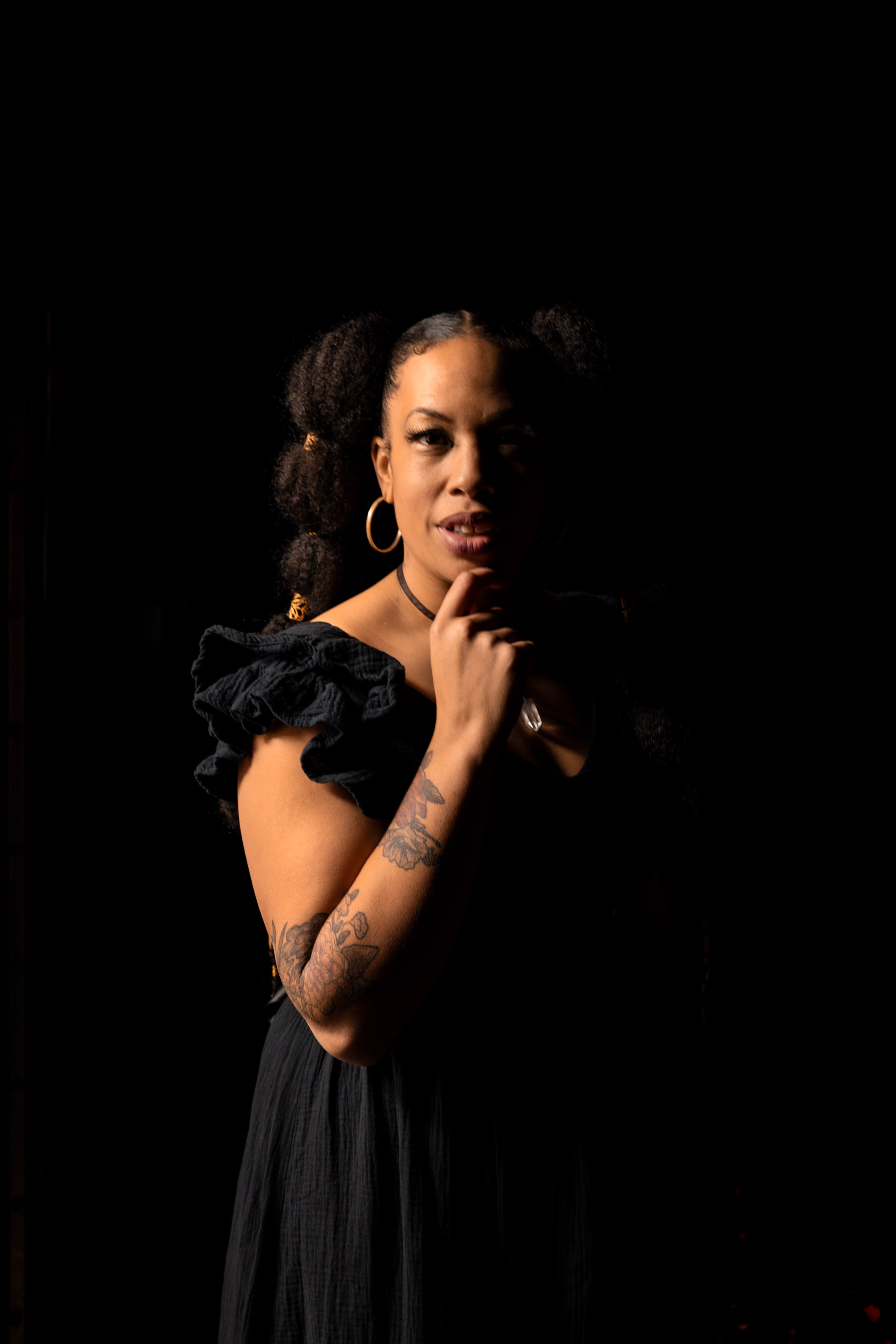 A portrait of the singer Lady Nade half illuminated and half in shadow.